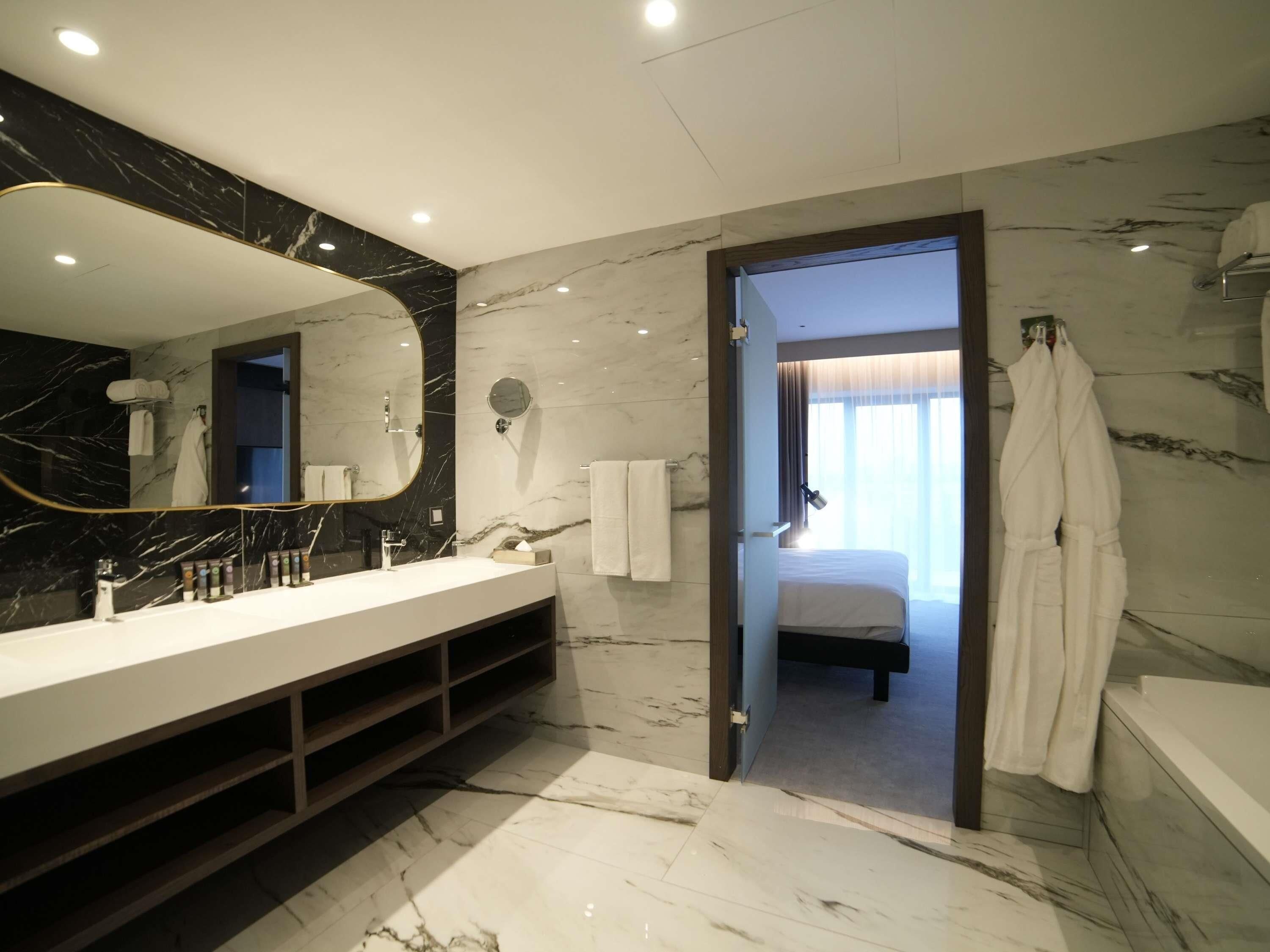 A modern bathroom with a marble vanity, a large mirror, and a walk-in shower.