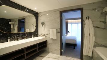 A modern bathroom with a marble vanity, a large mirror, and a walk-in shower.