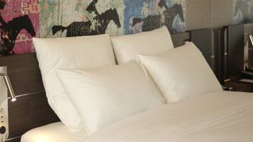 Un lit bien fait, avec du linge de lit blanc, une tête de lit moderne et un mur décoré d’œuvres d’art sur le thème du cheval.