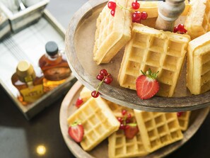 A wooden tray with waffles and strawberries. - Novotel Bishkek City Center (Bishkek)