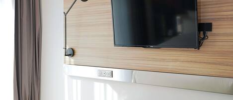 Una sala de estar moderna con un televisor de pantalla plana montado, una mesita auxiliar y una lámpara de pie.