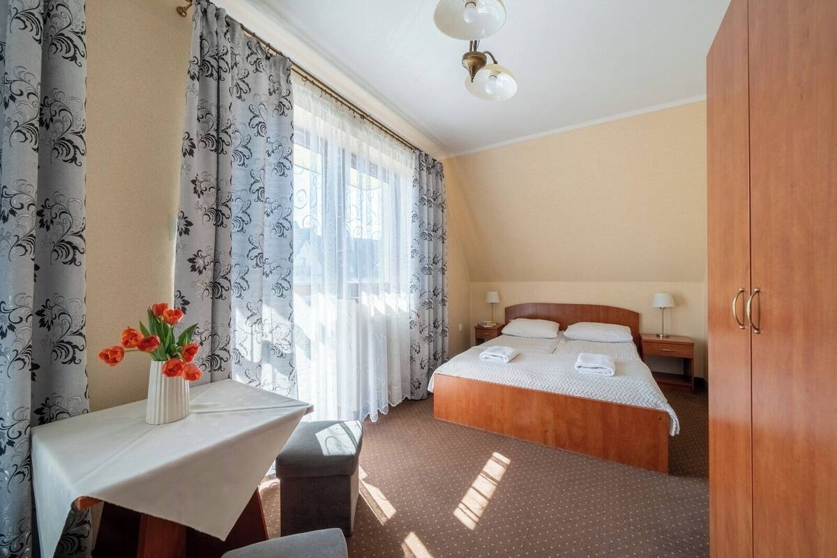 A hotel room with a bed, bedside tables, a desk, and a chair.