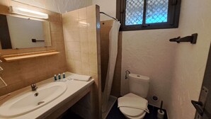 Een badkamer met een wastafel, spiegel, toilet en douche.