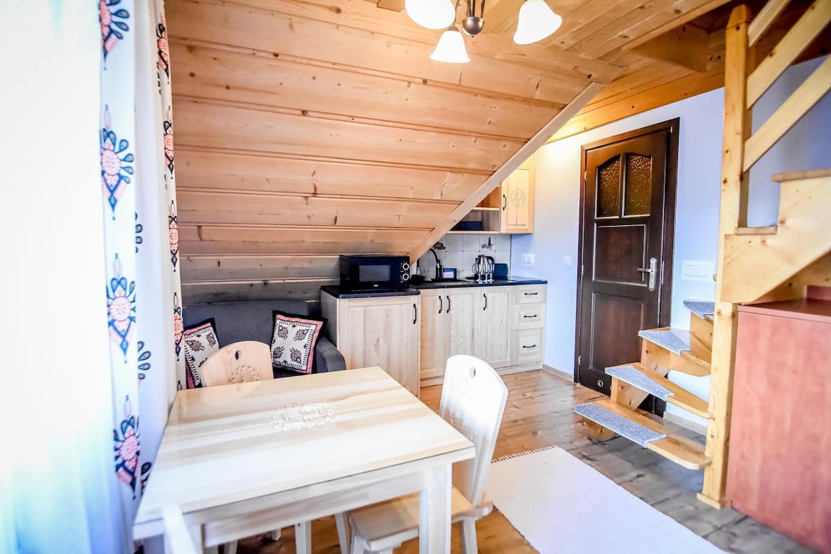 A cozy kitchen with wooden cabinets, a microwave, and a dining area with a table and chairs.