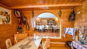 A wooden interior with a dining area, a kitchen visible through an archway, and horse tack on the walls. - Willa u Zwijacza (Zakopane)