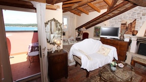 A cozy room with a bed, a television, and a view of the sea. - Apartments Milkana (Rovinj)