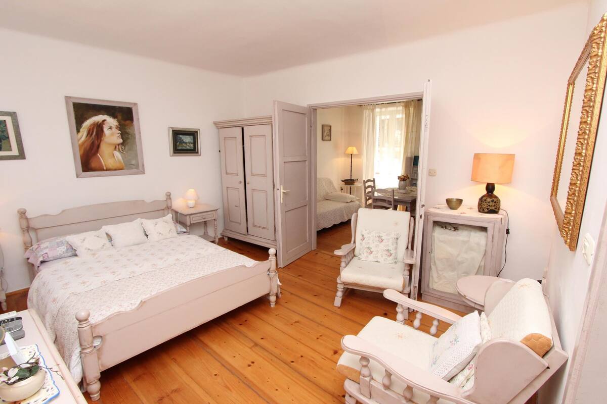 Un dormitorio con cama, una silla, cómoda y espejo.