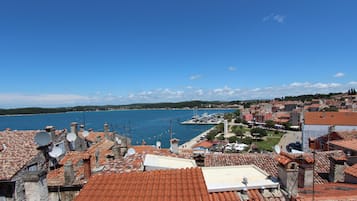 Un pueblo costero con edificios de tejados en tonos terracota, un puerto deportivo y un cielo azul despejado.