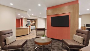 A hotel lobby with a reception desk, seating area, and a flat-screen TV mounted on the wall. - TownePlace Suites by Marriott Cedar Rapids Marion (Marion)