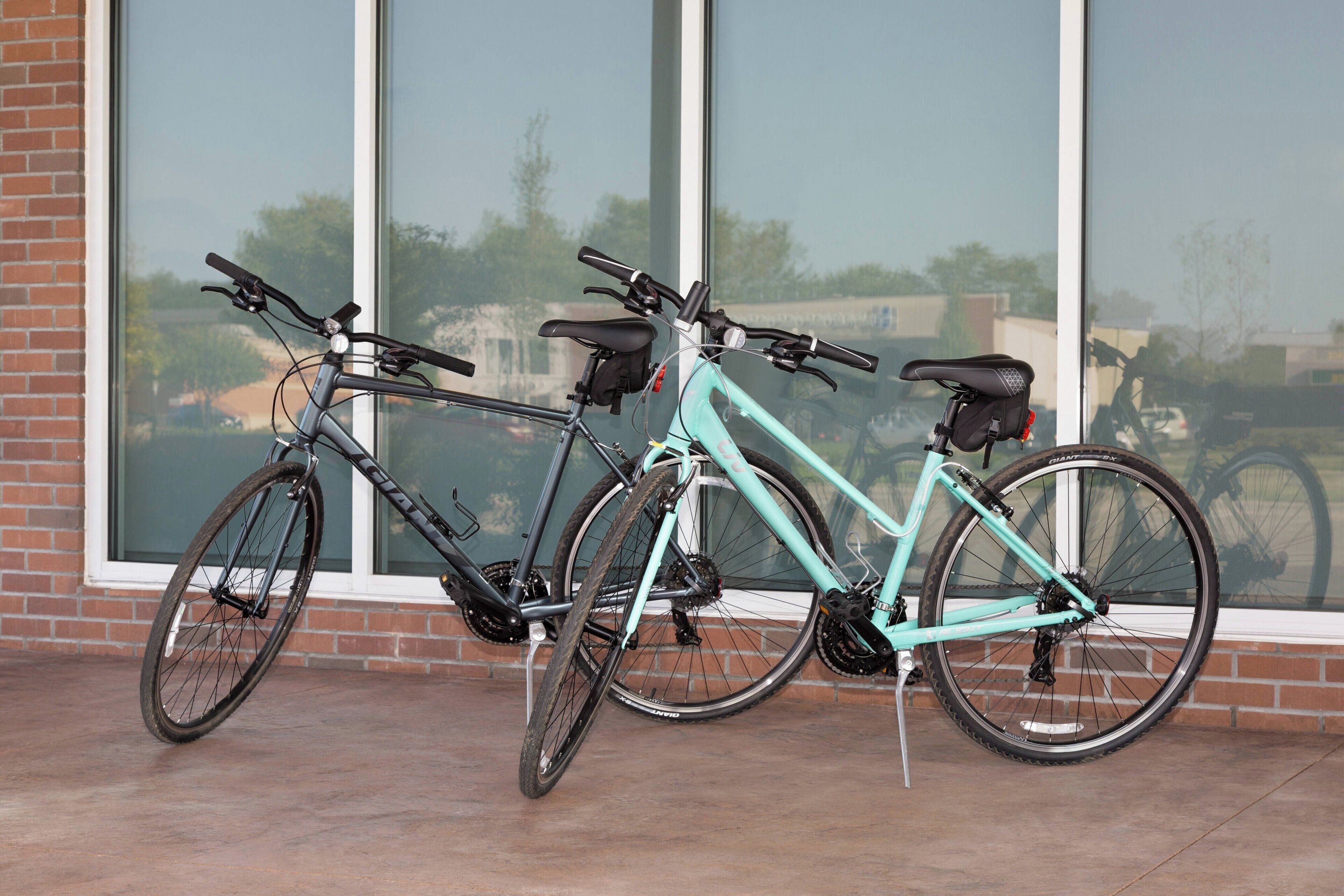 Dos bicicletas estacionadas frente a un edificio con grandes ventanales.