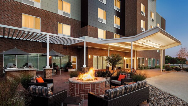 An outdoor patio area with a fire pit, seating, and a covered walkway. - TownePlace Suites by Marriott Cedar Rapids Marion (Marion)
