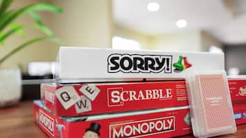 Conjunto de jogos de tabuleiro, incluindo Scrabble, Monopoly e Sorry!, sobre uma superfície de madeira.
