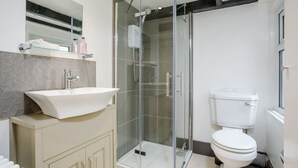 Une salle de bain moderne avec une douche à parois de verre, un lavabo blanc et des toilettes.