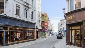 Une vue de rue avec des boutiques, dont une devanture visible avec des mannequins et une enseigne indiquant « JONES SOOTMAKER ».