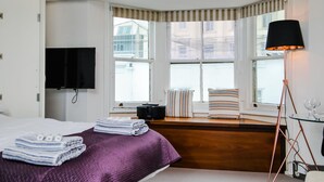 Une chambre d’hôtel avec un lit, une télévision, une fenêtre donnant sur un paysage agréable, une lampe et un radiateur.