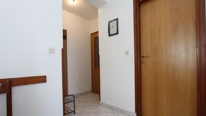 A hallway with a wooden door, a clock on the wall, and a chair. - Apartments Miriana (Rovinj)