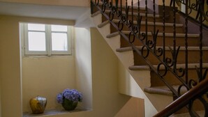 A staircase with ornate metal railings and a window with a vase of flowers.