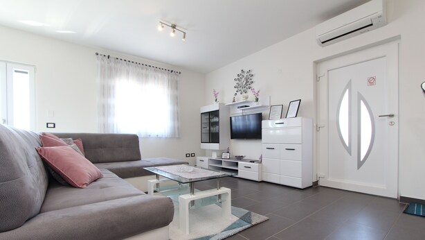 A modern living room with a sofa, TV, and white cabinetry. - Apartment Mondelaco (Rovinj)
