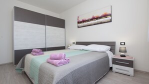 A modern bedroom with a large bed, a nightstand, a wall-mounted artwork, and a wardrobe. - Apartment Mondelaco (Rovinj)