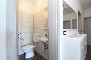 A bathroom with a toilet, sink, and storage cabinet.