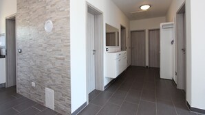 A hallway with a stone wall, white cabinets, and a tiled floor. - Apartment Mondelaco (Rovinj)