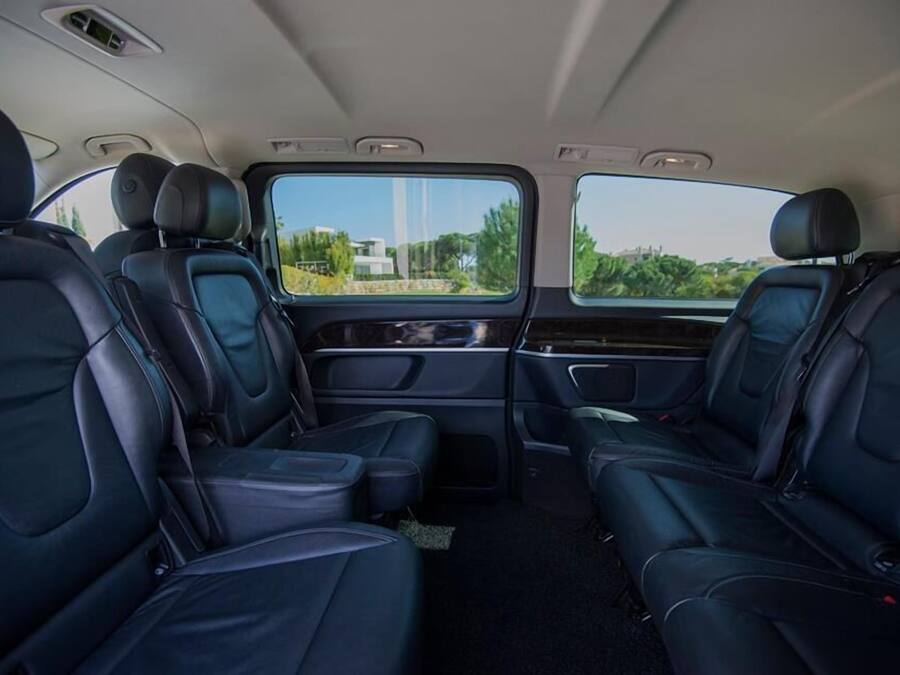 A car interior with black leather seats, a central console, and a view through the windows.
