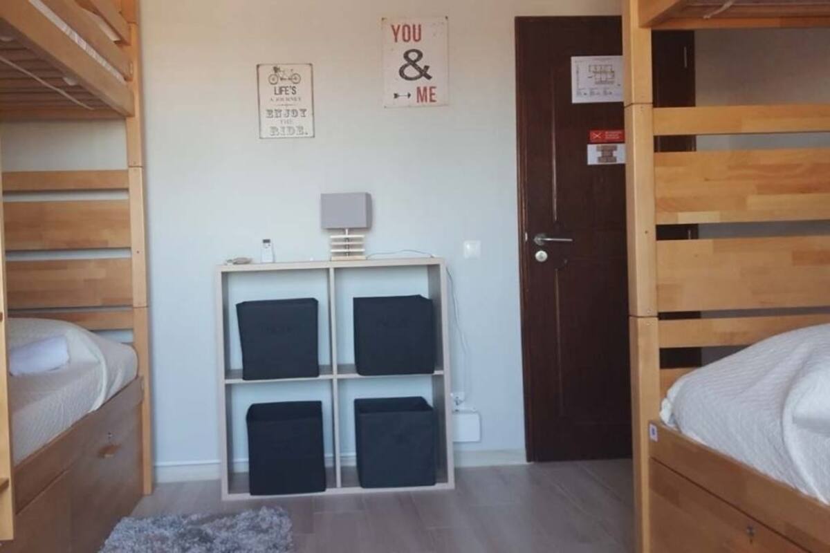 A room with bunk beds, a desk with storage, and a door with a sign.