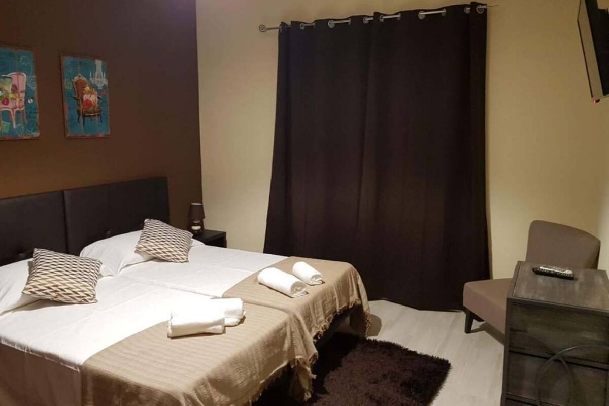 A hotel room with a bed, a chair, a desk, and a TV.