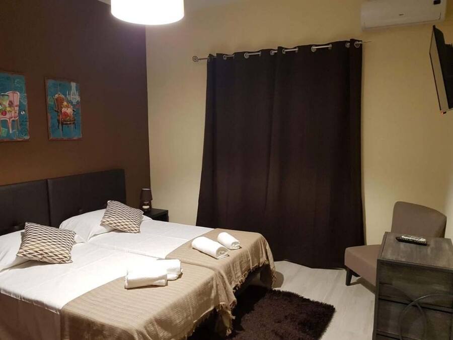 A hotel room with a bed, a chair, a desk, and a TV.
