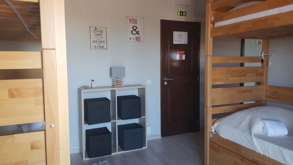 Een kamer met een stapelbed, een bureau met een lamp, opbergkisten en motiverende posters aan de muur.