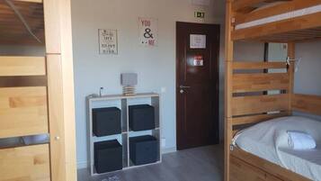 Een kamer met een stapelbed, een bureau met een lamp, opbergkisten en motiverende posters aan de muur.