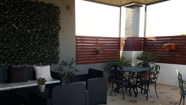 An outdoor patio with wicker furniture, a table, and potted plants. - Almancil Hostel (Loulé)