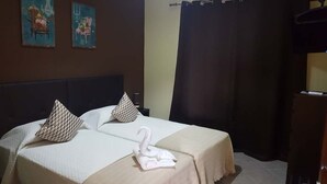 A double bed with two pillows, a swan-shaped towel, and two paintings on the wall. - Almancil Hostel (Loulé)