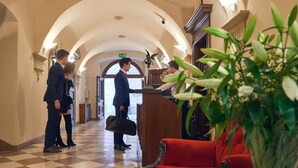A hotel lobby with a check-in counter, a red armchair, and a checkered floor. - Hotel Bogoria (Kraków)