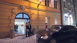 A black car parked in front of a building with an arched entrance and a light fixture above it. - Hotel Bogoria (Kraków)