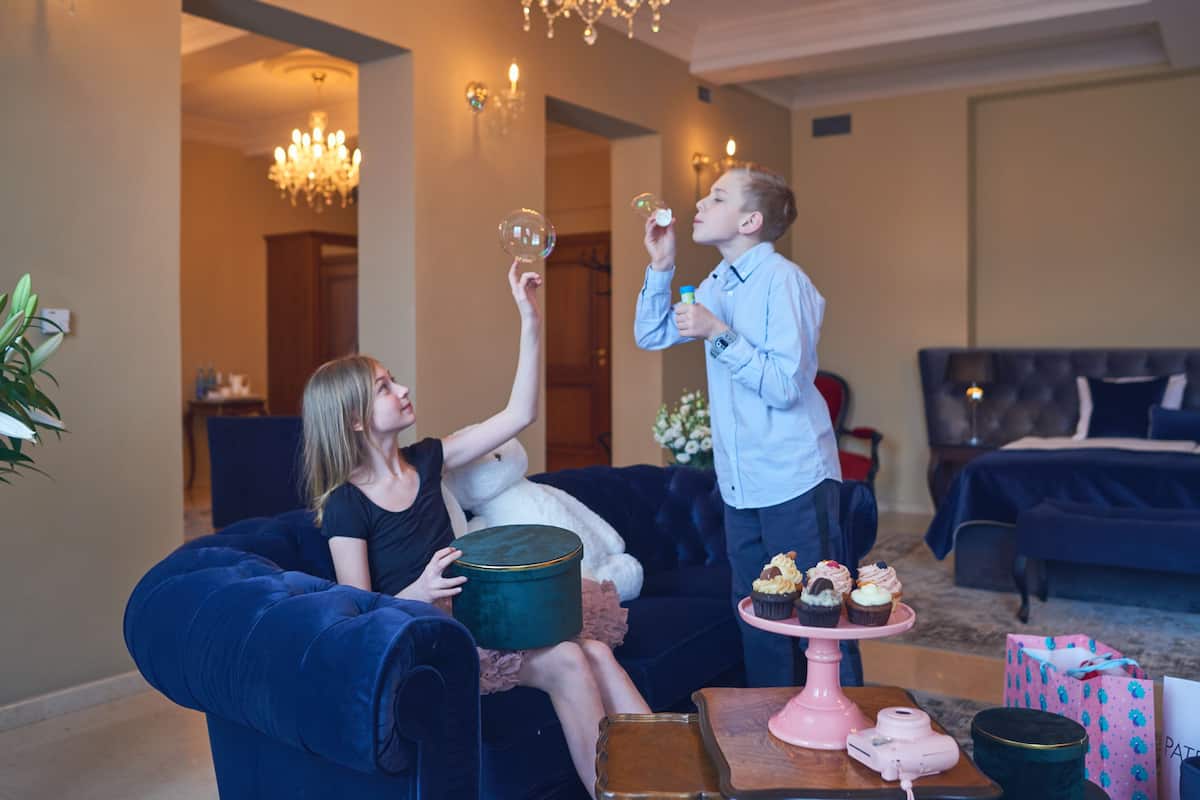 A living room with a blue sofa, a coffee table with cupcakes, and a chandelier.