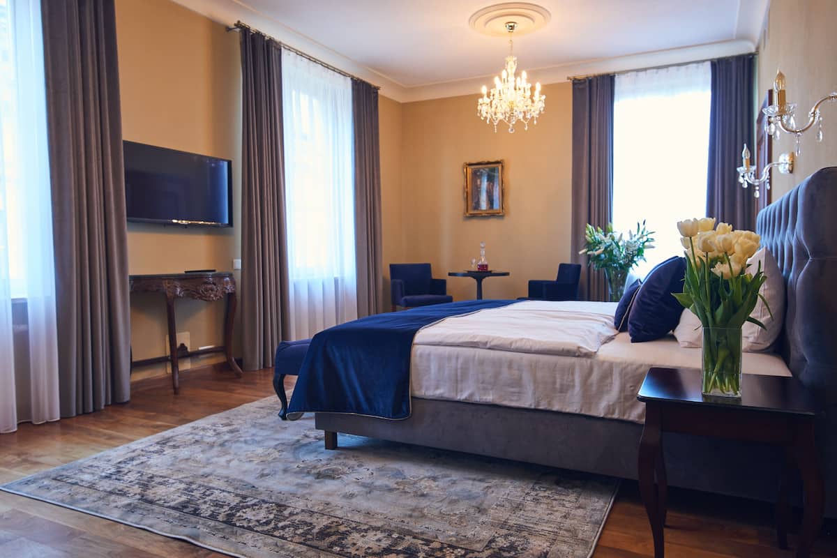 A bedroom with a bed, a TV, a desk, and a chandelier.