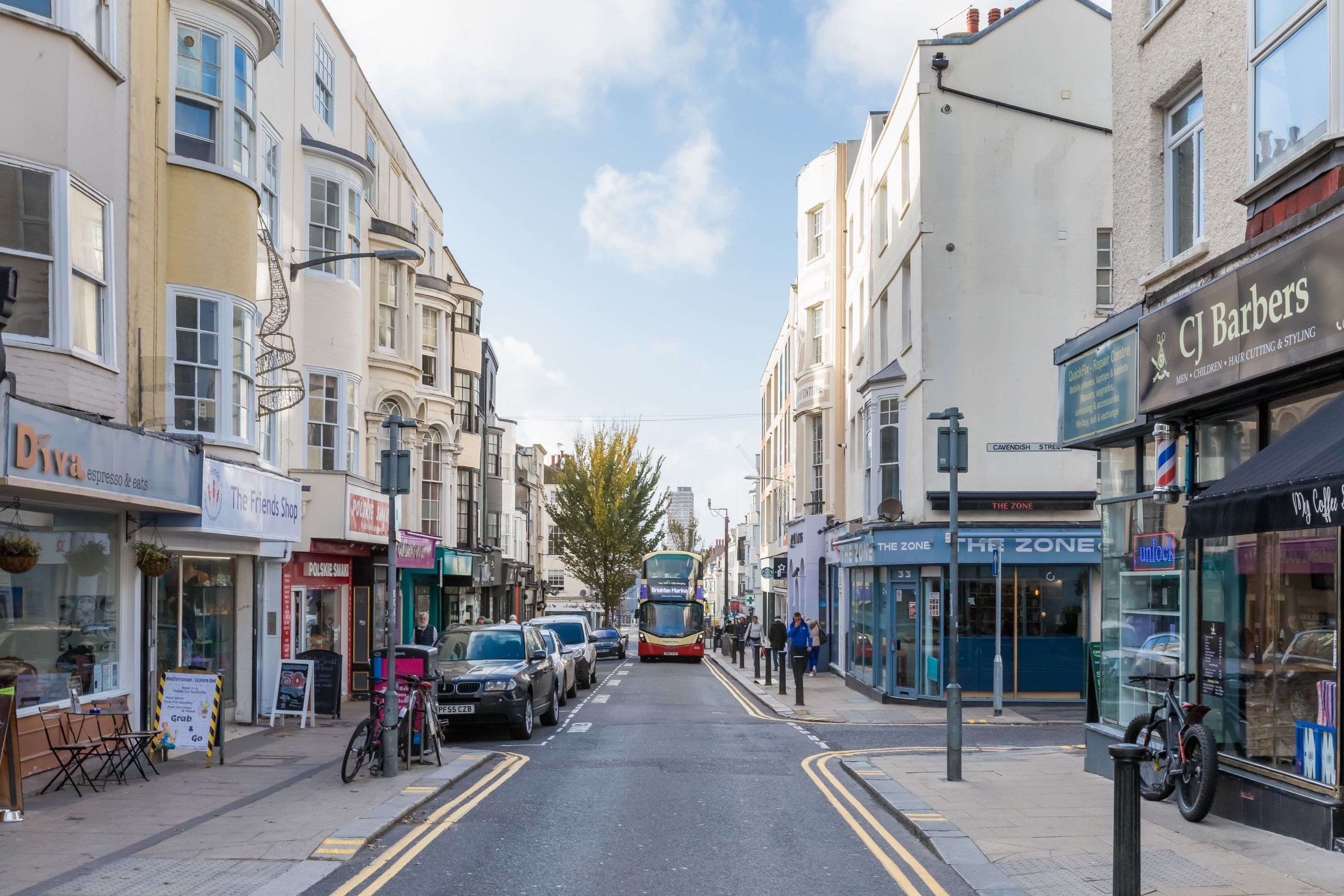 A street lined with shops and a double-decker bus approaching.
