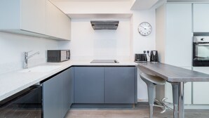 Une cuisine moderne équipée d’un four à micro-ondes encastré, d’une machine à café et d’une horloge murale.