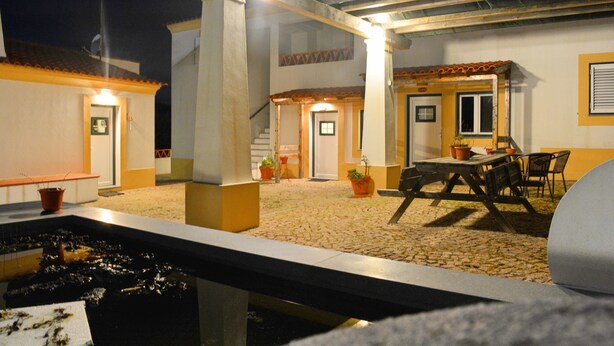 Un espace extérieur aménagé en terrasse, avec un sol en pierre, une piscine et une table entourée de chaises.