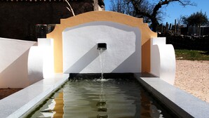 Un élément décoratif aquatique rectangulaire, doté d’une fontaine centrale, et entouré d’une structure blanche et beige.