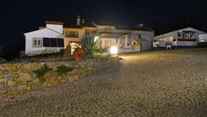 Une maison avec un mur en pierre, une allée et un véhicule garé à proximité.