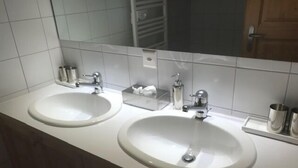 A bathroom with two sinks, a mirror, and a towel rack. - Bright and warm apartment for up to 4 people, on the ground floor of a chalet with two apartments. I (St-Luc)
