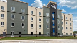 Un bâtiment moderne à plusieurs étages abritant un hôtel Sleep Inn & Suites, avec un logo bien visible sur la façade.