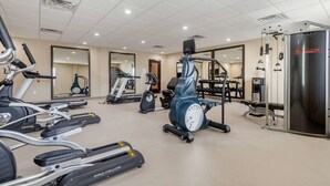 Une salle de sport équipée de divers appareils d’exercice, notamment des tapis de course, un vélo elliptique et une machine de musculation.