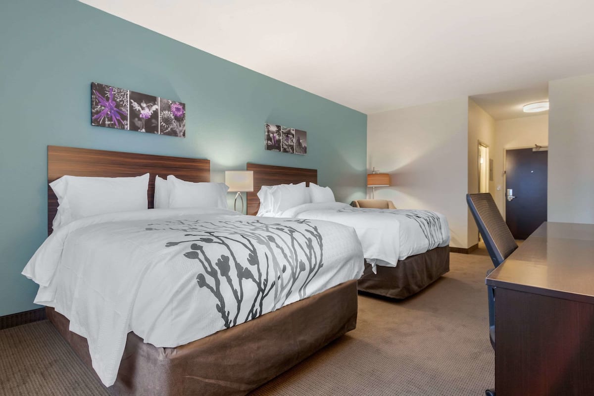 Ein Hotelzimmer mit zwei Betten, einem Schreibtisch und Bildern an den Wänden.
