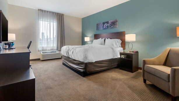 Une chambre d’hôtel avec un lit, un bureau, une chaise et une fenêtre avec des rideaux.