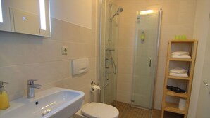 A bathroom with a sink, toilet, and glass-enclosed shower. - Coach house - Small house on two levels (Quedlinburg)