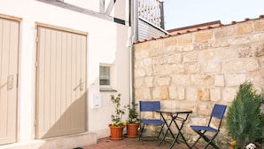 A patio with a stone wall, a wooden door, and two folding chairs. - Coach house - Small house on two levels (Quedlinburg)