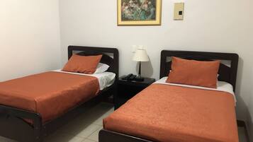 Two single beds with matching headboards and footboards, a bedside table with a lamp, and a framed painting on the wall.
